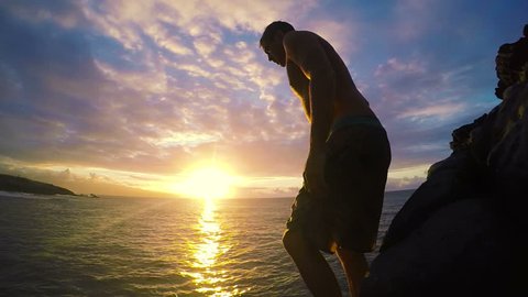 Young Man Does Front Flip off Clip into Ocean at Sunset at Medium Speed.
: stockvideo
