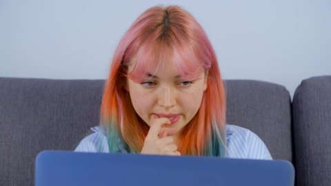 Professional freelancer white woman working on computer. Caucasian young girl with dyed hair typing on laptop while doing distant work from home on lockdown. Focused and busy free lance worker female