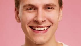 Cropped Shot Of Happy Guy Smiling Looking At Camera Over Pink Background In Studio. Closeup Portrait Of Millennial Man Expressing Positive Emotions. Slow Motion