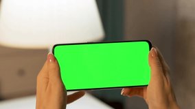 Woman's Hands Hold Horizontally Phone with Green Screen, Green Background, Chroma key, Close-up. Video Communication, Advertising, Advertising Product, Internet Search, Social Networking Browsing.
