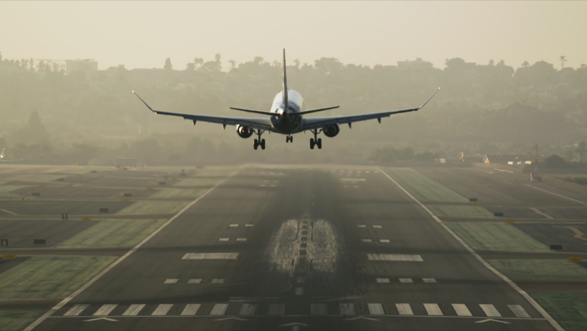 Big commercial plane serving domestic flight as seen from above. Huge aircraft landing on a runway with a cityscape behind. High quality 4k footage