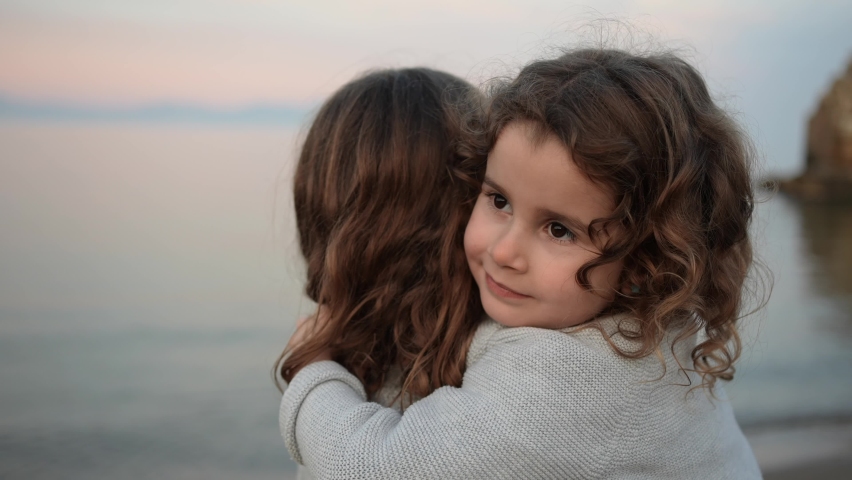Portrait of a little girl hugging her sister on the beach with sea in the background. Royalty-Free Stock Footage #1084844647