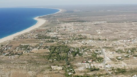 Slow motion aerial view of the neighborhoods of Todos Santos with houses on a sunny day in a natural background Baja, Mexico