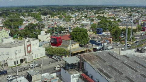 Santo Domingo , Dominican Republic - 12 09 2021: Aerial drone view following cable cars, riding over the ghetto of Santo Domingo