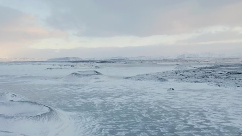 Drone flight over frozen Mývatn Lake and Volcanic Crater covered with snow during cold winter day - Breathtaking Winter Scene of North Iceland