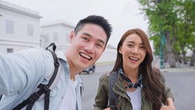 POV Asian couple backpacker use mobile phone take a video clip in city. Attractive man and woman tourist traveler travel on street, using smartphone record vlog on holiday vacation trip in Thailand.