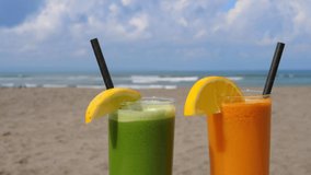 Green and orange refreshing tropical drinks in glasses on the sandy beach with ocean waves and sky in the background - Powered by Shutterstock - Get 15% off with code: PIKWIZARD15