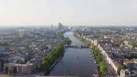 Inscription on video. Amsterdam, Netherlands. Flying over the city rooftops. Amstel River. Different colors letters appears behind small squares, Aerial View
