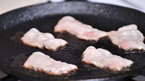 preparing breakfast. frying bacon close-up slow mo