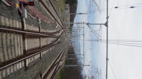 view from the last window of a railway passenger car, railway tracks stretching into the distance, vertical video