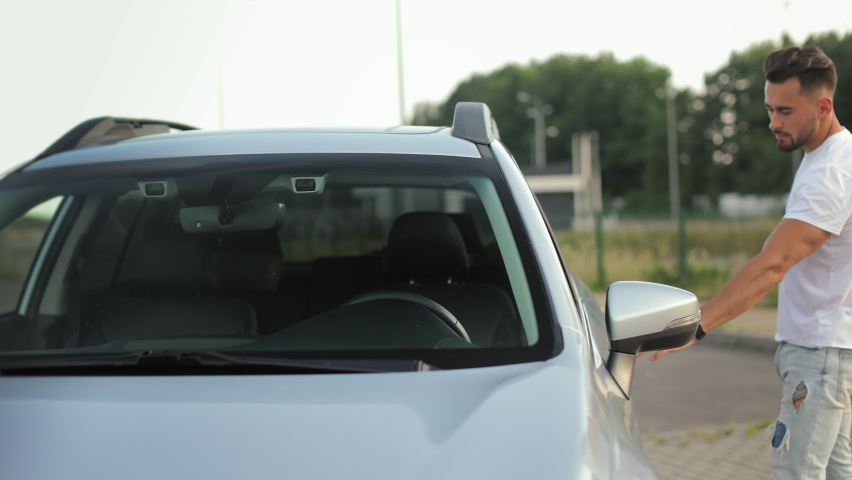 A man is going to the car. He is opening the door and sitting in the driver