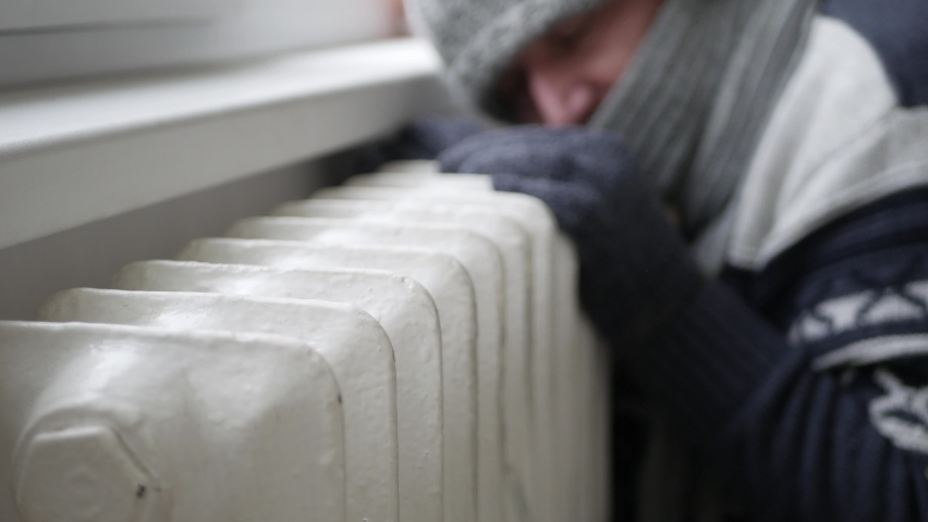 Elderly Person Wearing Winter Clothes Tremble Trying to Warmth Near a Hot Radiator at Home. Global Energy Crisis Concept. Royalty-Free Stock Footage #1084870501