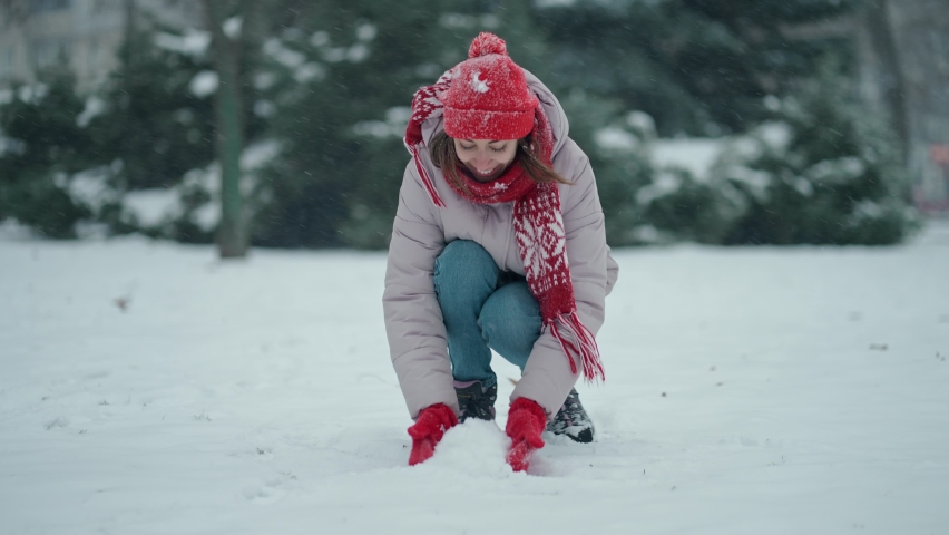 sliw motion girl at winter time walks and haves fun outdoors. cheerful excited woman throws snow up and rejoices in flying snowflakes at windy frosty winter day.