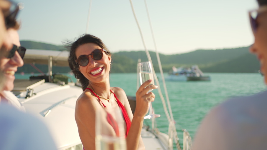 4K Group of man and woman friends enjoy party drinking champagne together while catamaran boat sailing at summer sunset. Male and female relax outdoor lifestyle on sail yacht tropical travel vacation Royalty-Free Stock Footage #1084872961