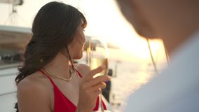 4K couple enjoy outdoor luxury party drinking champagne with talking together while catamaran boat sailing at sunset. Man and woman relax with outdoor lifestyle on summer travel vacation - Powered by Shutterstock - Get 15% off with code: PIKWIZARD15