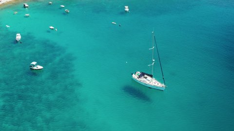 Drone footage of white yachts and boats in the sea with turquoise clear water.