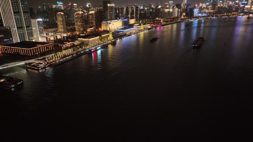 Drone aerial view of waterfront of Shanghai Huangpu River in night. Landmark river and cityscape skyline in China. Travel tourism transportation and business concept b-roll footage. The bund area