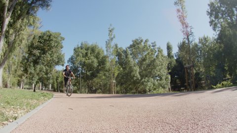 Long shot of man with disability doing trick on bike outdoor. Handheld shot of focused Caucasian sportsman with artificial leg pedaling, standing on wheel, jumping. Disability, extreme sport concept