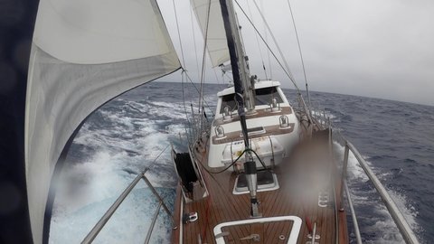 Storm in the Drake Passage on a sailing yacht trip to Antarctica. The view from the the bow of the yacht to the captain's cabin against the backdrop of large ocean waves. Adventure travel lifestyle.