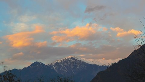 4K Time-lapse of the snow covered mountain during the morning at Manali in Himachal Pradesh, India. Early morning yellow light hits the peak of the snow covered Himalayan mountain turning it orange.  