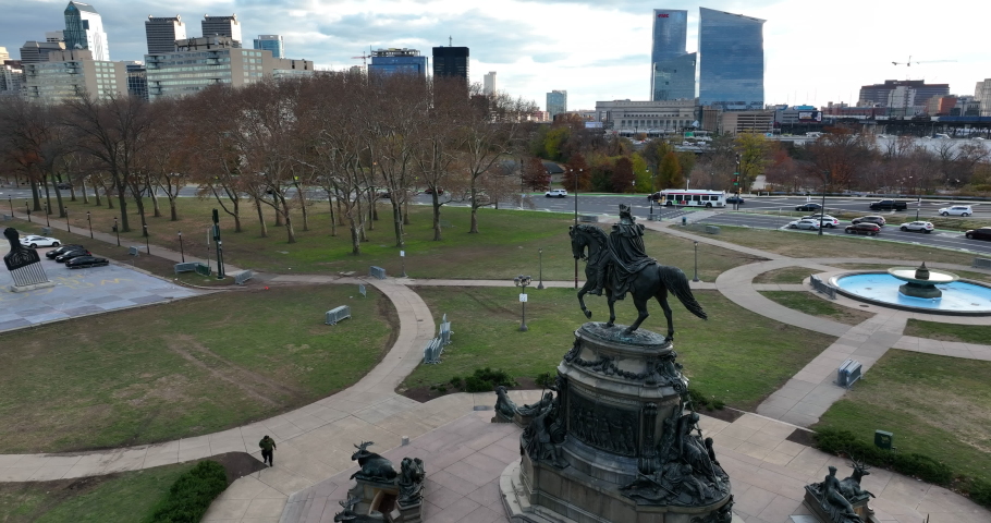 Aerial reveal of Benjamin Franklin Parkway from George Washington on horseback monument. Philly skyline.