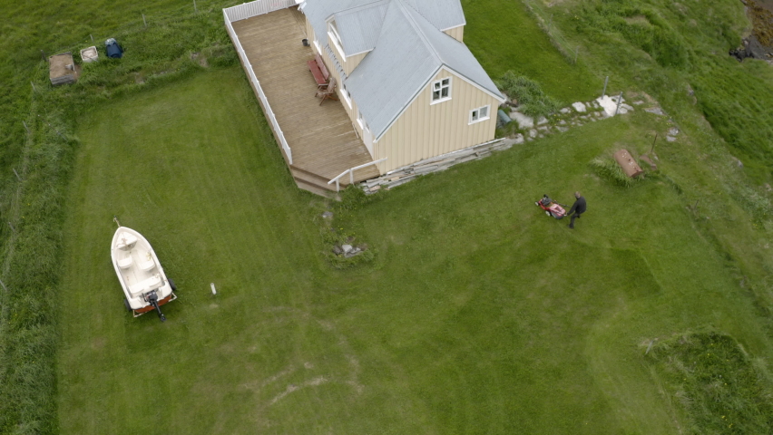 Top View Of A Man Mowing Lawn Near Flatey Church In Iceland. Aerial Topdown