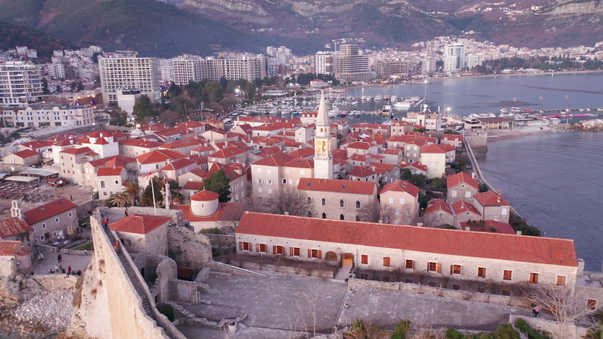 Budva Montenegro old town on Mediterranean sea coast - red roofs on white medieval stone houses featuring church bell tower. Landmark and tourist vacation destination in Europe at dawn or dusk.