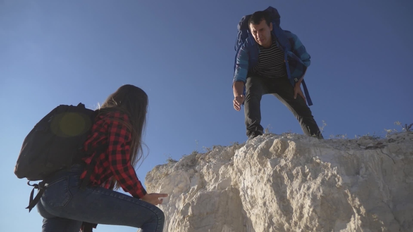 Teamwork. A couple of tourists lend a helping hand while climbing the cliff to the top of the mountain. The path to success in teamwork. Family hiking. A helping hand to overcome difficulties. Royalty-Free Stock Footage #1084884307
