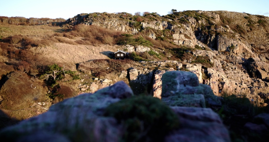 Cabin on the edge of a mountain during sunset with steep cliffs around