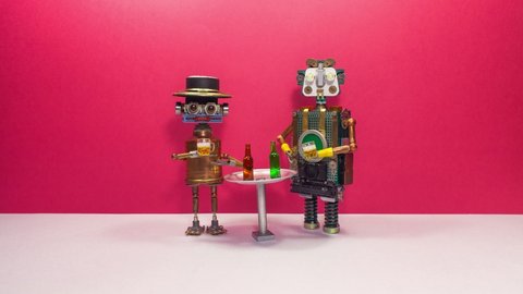 Birthday celebration party. Two funny friendly robots drink beer, clink glasses and offer to drink with them. The concept of a beer party or meeting of friends in a bar, pub or restaurant.
