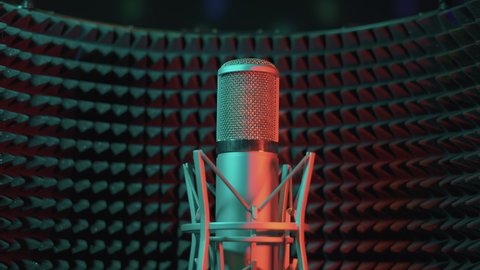 Studio professional tube microphone in a recording studio on the background of an acoustic screen. The camera moves smoothly from right to left while holding the microphone in the center and in focus.