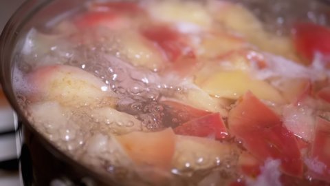 Cooking Healthy Apple Compote, Boiled Compote in a Boiling Saucepan on Gas Stove. Vitamin stewed fruit from fresh red apples. Boiling process, formation of steam, foam, bubbles on the water surface.