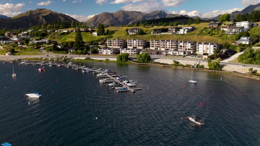 Lakeside with modern hotels and small port. Wanaka, New Zealand. Aerial birds eye during sunny day.