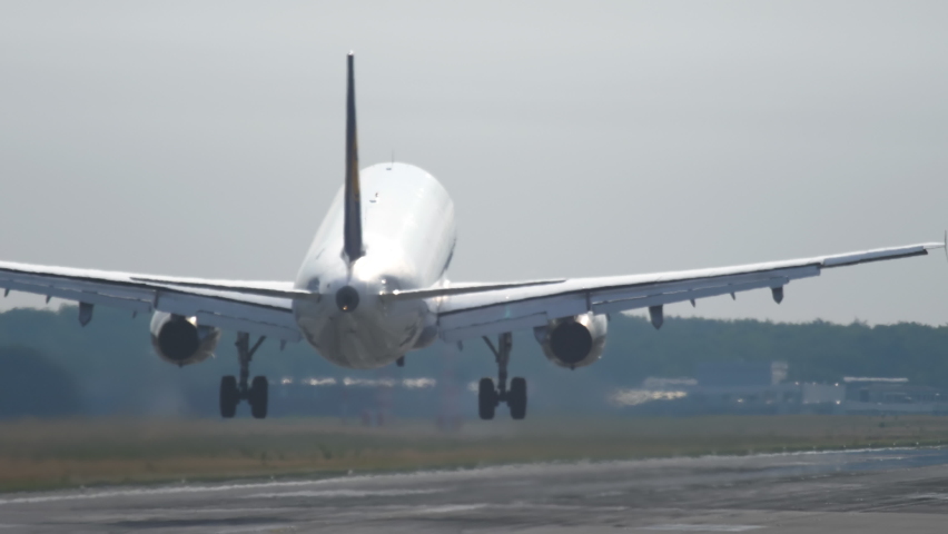 Jet airliner landing on runway. Back view on landing airplane. Small jet aircraft arriving at international airport on summer day. Chassis touching down runway with smoke. Royalty-Free Stock Footage #1084896301