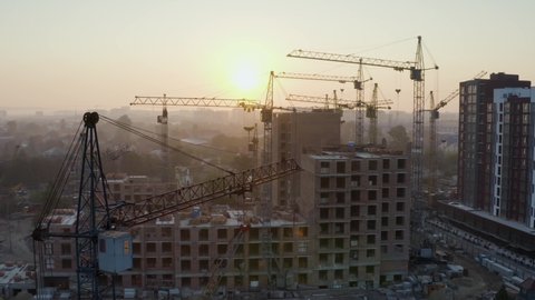 Hoisting iron cranes at a foggy sunrise over the construction of a new block in Ukraine, Ivano-Frankivsk (old houses were demolished first)