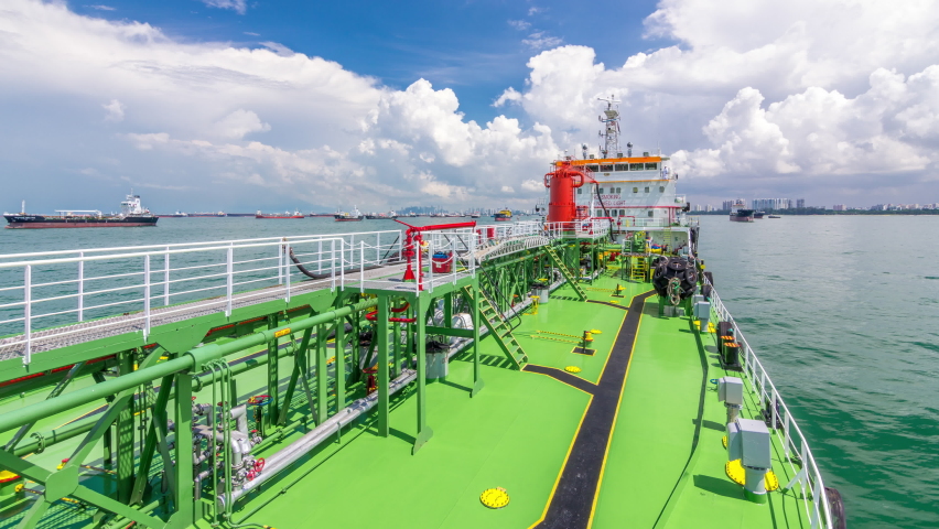 Green deck of the tanker under blue cloudy sky timelapse. Red crane with pipe mooving on it by operator.