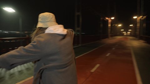 Close-up. Stylish, girl dancing House dance style, right in front camera. Moving camera around. Waving his arms, night winter, cold autumn, bridge, against background big city, river, road, cars