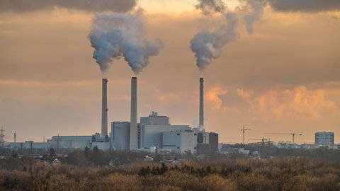 Timelapse toxic enterprise chimneys tubing against the sky background release black smoke. Factory pollutes environment. Munich Germany countryside landscape. Winter day. 