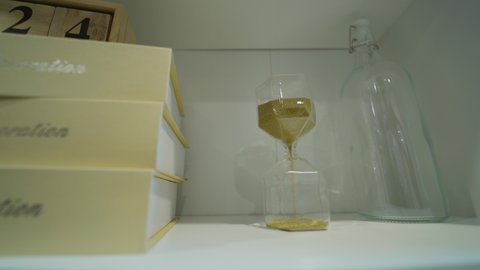 hourglass with golden sand pouring inside, eternal time, infinity, business time Time passing concept,urgency and running out of time. Sand fall in hourglass hourglass on bookshelf