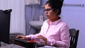 Indian woman in pink dress working on computer at home and feeling exhausted