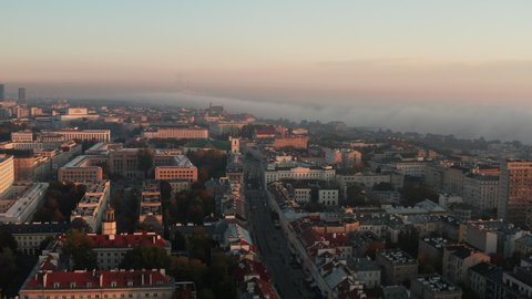 Forwards fly above morning town, buildings in midtown. Fog around river in background. Warsaw, Poland