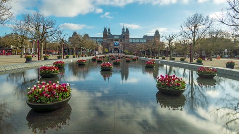 Amsterdam, Netherlands - April 14th 2021: Time lapse of the Rijksmuseum in Amsterdam on a spring morning with tulips in the water and reflections