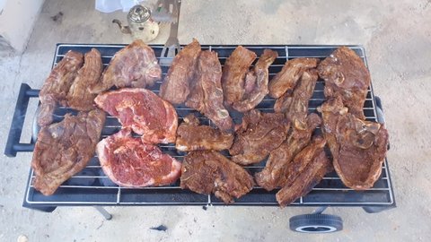Top view of variety of meat being grilled on a small mobile grill outside