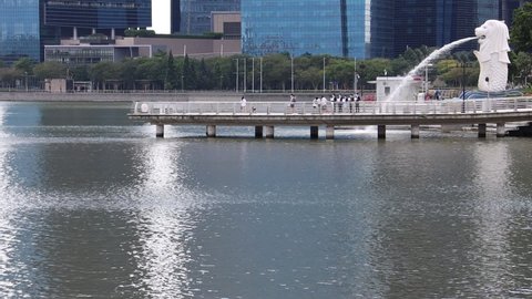 SINGAPORE - 6 JAN 2022, 1 PM: Merlion Park has few tourists due to the Covid-19 pandemic. There are a group of suited men singing and a few cyclists going to the Jubilee Bridge. 