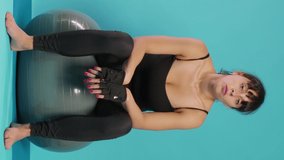 Vertical video: Tired woman taking break and breathing after intense workout practice, recovering from physical muscle exercise on fitness toning ball. Active person doing pilates activity in studio.