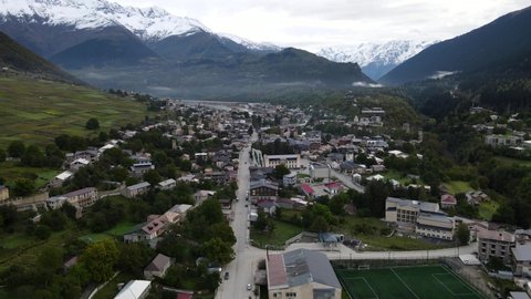 Aerial view on Mestia, Svaneti, Georgia. Cloudy summer day, snowy peaks of the mountain range. Historic heritage of Svan towers and residential houses.