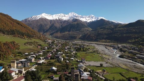 Aerial view on Mestia, Svaneti, Georgia. Sunny summer day, snowy peaks of the mountain range. Historic heritage of Svan towers and residential houses.