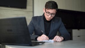 Young man, businessman in glasses, sitting at the workplace in the office at home with a laptop, online work and education, online store sales, video communication zoom.