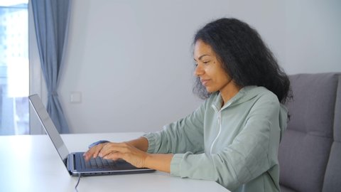 Professional freelancer woman working on laptop computer with happy smile. African female doing freelance work online on lockdown. Free lance writer person typing text on notebook keyboard in 4k video