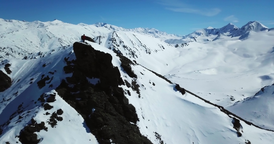 Aerial Panning Shot Of Male Tourist On Snowy Rock Formation Top During Sunny Day - Interior Alaska, Alaska